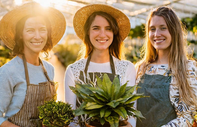 women history month: three women smiling holding their potted plants